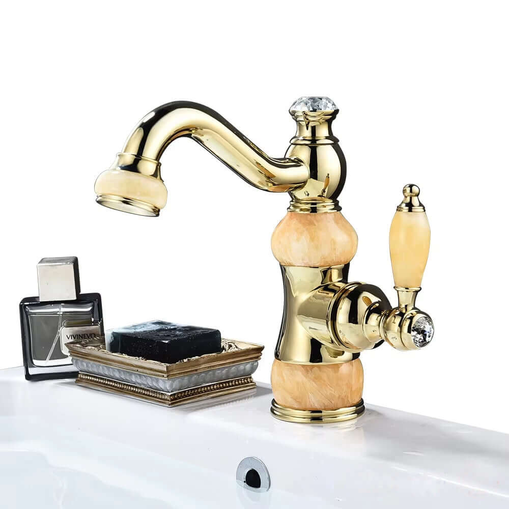 Luxury golden basin faucet with a unique design and single handle, showcased beside a soap dish and fragrance bottle.