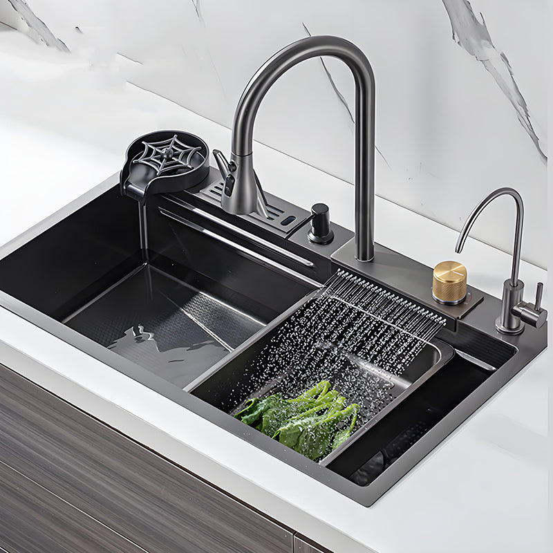 Black waterfall multifunctional stainless steel workstation kitchen sink installed in a white countertop with high-arc faucet, cup washer, auxiliary faucet, gold control knob, and wide rinsing outlet washing vegetables.