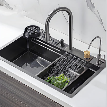 Black waterfall multifunctional stainless steel workstation kitchen sink installed in a white countertop with high-arc faucet, cup washer, auxiliary faucet, gold control knob, and wide rinsing outlet washing vegetables.