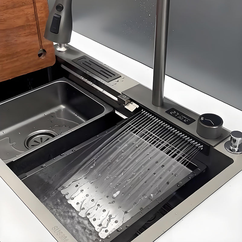 Close-up of waterfall multifunctional stainless steel kitchen sink with wide waterfall outlet, perforated drain tray, control knob, faucet deck, and inner basin for rinsing and draining.