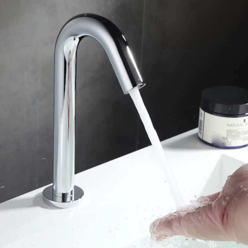 Countertop mounted sensor faucet with modern design, flowing water, and hand for hygienic use.